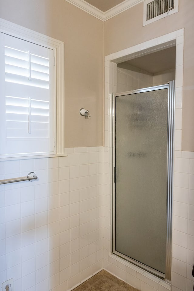 bathroom with tile walls, ornamental molding, and an enclosed shower