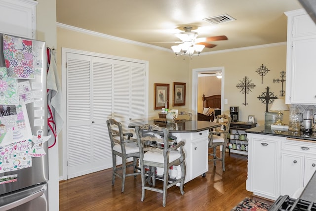 kitchen with white cabinetry, stainless steel fridge, dark hardwood / wood-style floors, and ornamental molding