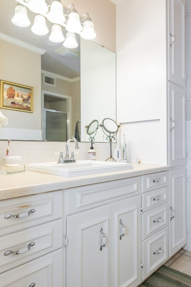 bathroom with vanity, tile patterned flooring, crown molding, and decorative backsplash