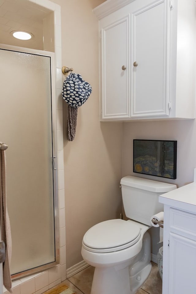 bathroom featuring vanity, a shower with door, toilet, and tile patterned floors