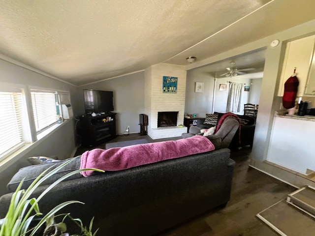 living room with lofted ceiling, ceiling fan, a fireplace, and a textured ceiling