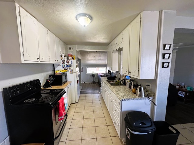 kitchen featuring white cabinetry, sink, light tile patterned floors, and black appliances