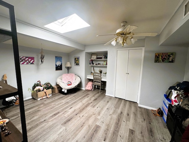 interior space with hardwood / wood-style flooring, built in features, ceiling fan, and a skylight