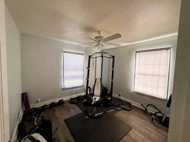 workout room with ceiling fan, a textured ceiling, and light wood-type flooring