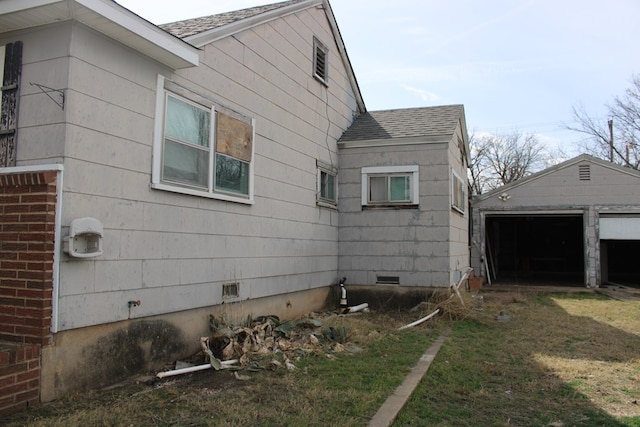 view of side of home featuring an outbuilding, a garage, and a yard