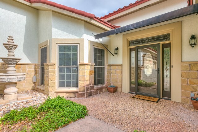 6026 Warwick Dr, San Angelo, TX 76901 - doorway to property with stucco siding, stone siding, and a tiled roof