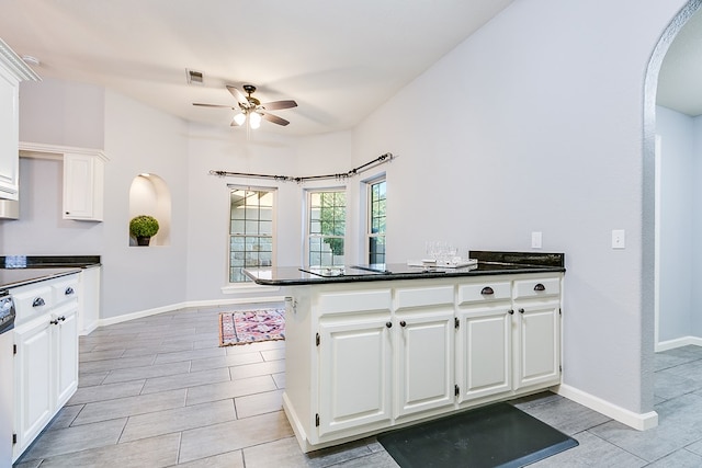 6026 Warwick Dr, San Angelo, TX 76901 - kitchen with arched walkways, ceiling fan, dark countertops, and white cabinets