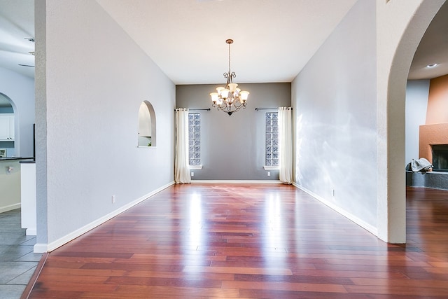 6026 Warwick Dr, San Angelo, TX 76901 - unfurnished dining area with hardwood / wood-style floors, a chandelier, arched walkways, and baseboards