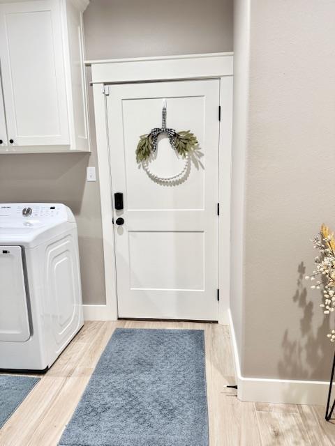 laundry area featuring cabinets, washer and clothes dryer, and light hardwood / wood-style flooring