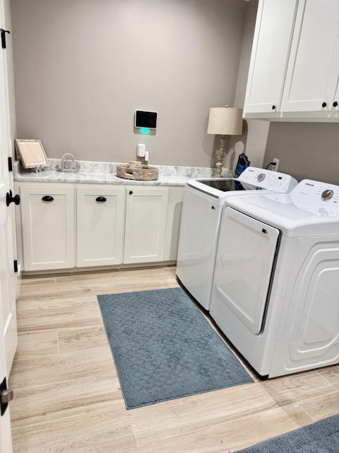 laundry room with washer and dryer, cabinets, and light wood-type flooring