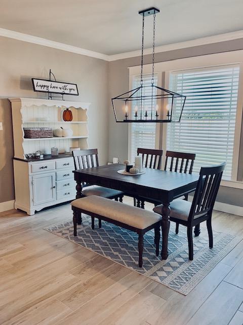 dining space featuring ornamental molding, an inviting chandelier, and light wood-type flooring