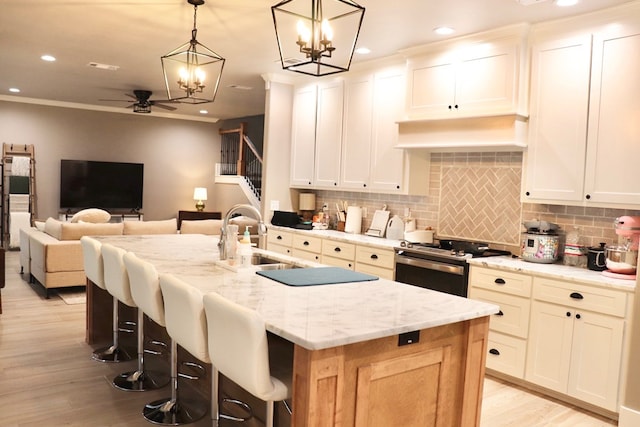 kitchen with stainless steel range with electric cooktop, a kitchen island with sink, and white cabinets