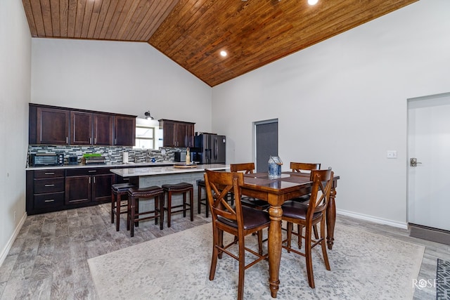 dining room featuring wood ceiling, light hardwood / wood-style flooring, and high vaulted ceiling