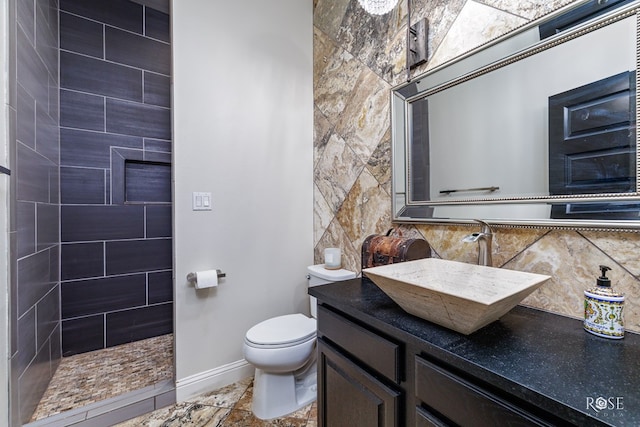 bathroom featuring vanity, toilet, decorative backsplash, and a tile shower