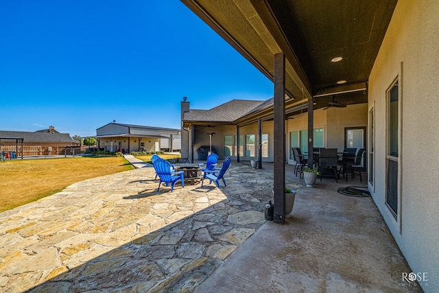 view of patio with ceiling fan and a fire pit