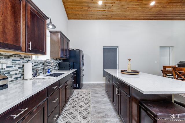 kitchen with sink, backsplash, a kitchen bar, light hardwood / wood-style floors, and wooden ceiling