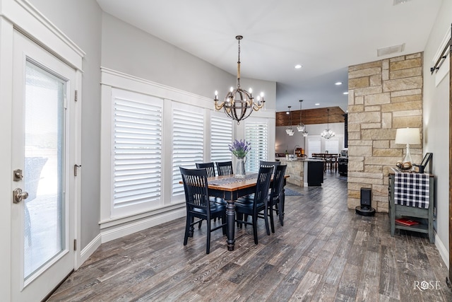 dining room with an inviting chandelier, a healthy amount of sunlight, and dark hardwood / wood-style flooring