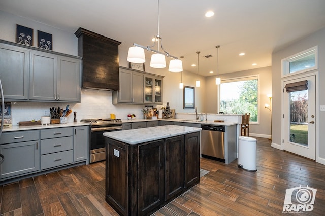 kitchen with premium range hood, decorative light fixtures, a kitchen island, stainless steel appliances, and decorative backsplash