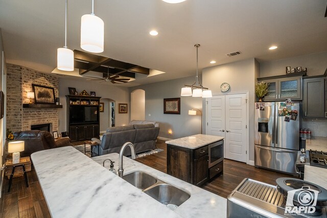 kitchen with appliances with stainless steel finishes, decorative light fixtures, sink, dark wood-type flooring, and a center island with sink