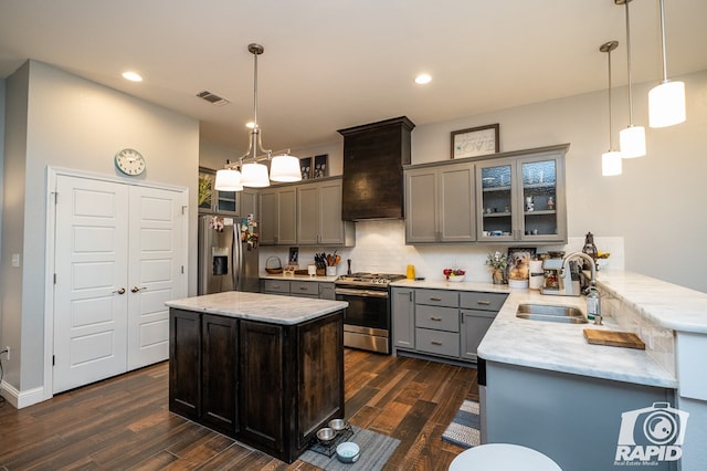 kitchen featuring sink, hanging light fixtures, dark hardwood / wood-style floors, kitchen peninsula, and stainless steel appliances