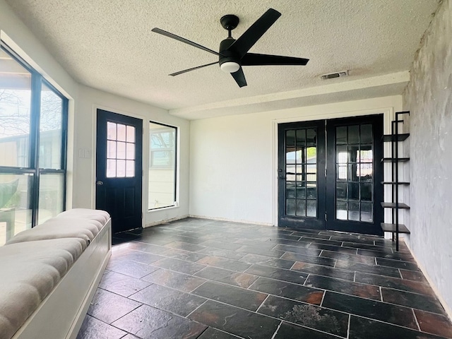 interior space featuring ceiling fan, a textured ceiling, and french doors