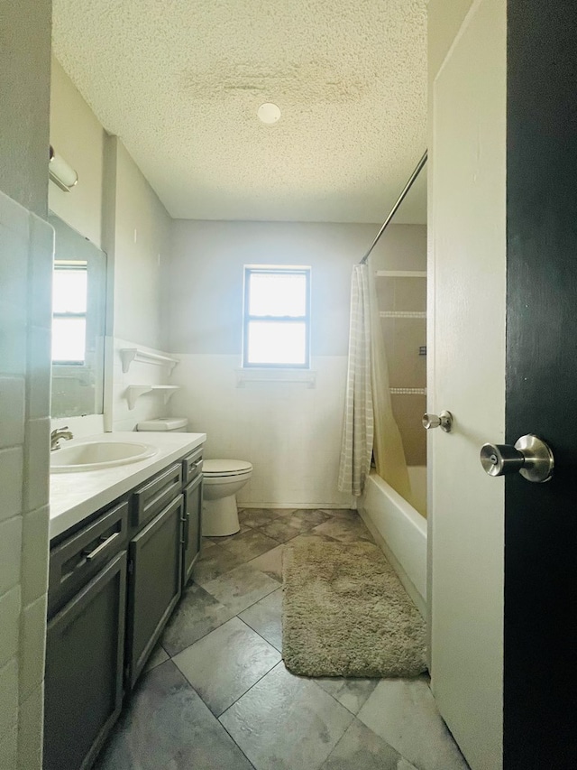 full bathroom with toilet, a textured ceiling, tile walls, vanity, and shower / bath combo with shower curtain