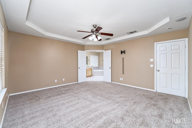 carpeted spare room with ceiling fan, a raised ceiling, and a textured ceiling