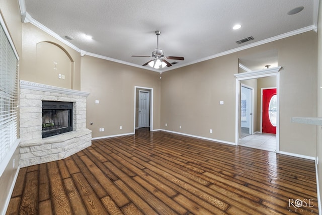 unfurnished living room featuring crown molding, a stone fireplace, wood-type flooring, and a textured ceiling