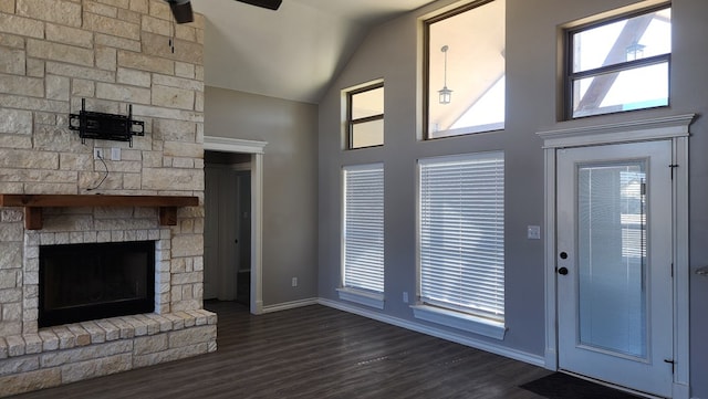 unfurnished living room with a stone fireplace, dark hardwood / wood-style floors, and a healthy amount of sunlight