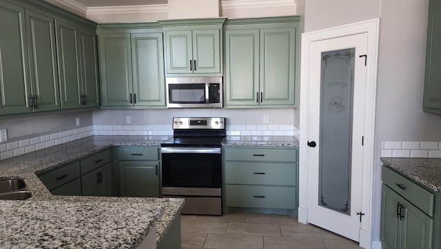 kitchen featuring stainless steel appliances, light tile patterned flooring, ornamental molding, and green cabinets