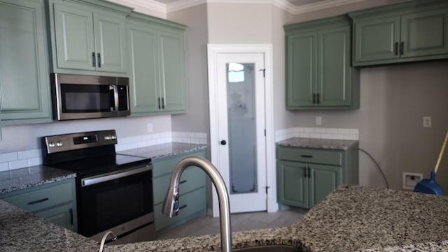 kitchen featuring green cabinetry, appliances with stainless steel finishes, and ornamental molding