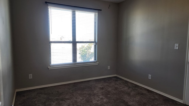 spare room featuring dark carpet