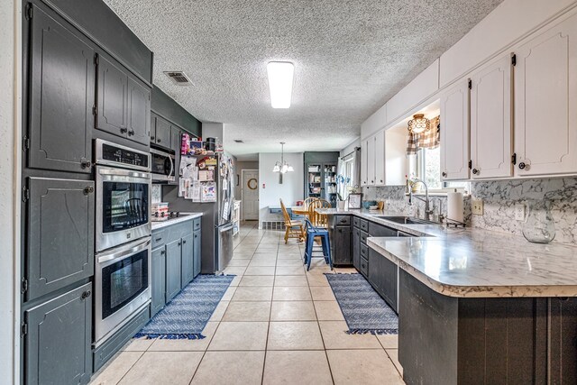3213 Sunset Dr, San Angelo, TX 76904 - kitchen featuring stainless steel appliances, a peninsula, a chandelier, a sink, and light countertops