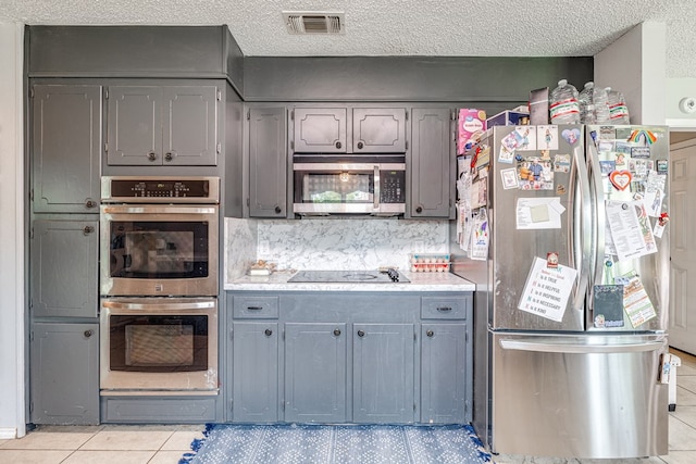 3213 Sunset Dr, San Angelo, TX 76904 - kitchen with stainless steel appliances, light countertops, light tile patterned floors, gray cabinetry, and a textured ceiling
