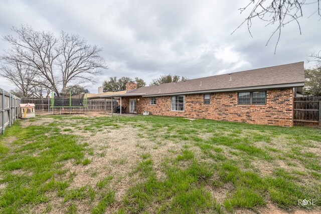 3213 Sunset Dr, San Angelo, TX 76904 - rear view of house featuring a trampoline, brick siding, and a chimney
