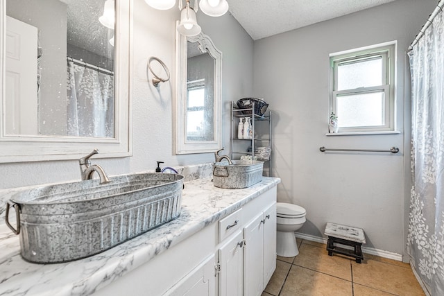 3213 Sunset Dr, San Angelo, TX 76904 - full bathroom with a textured ceiling, toilet, tile patterned floors, double vanity, and a shower with curtain