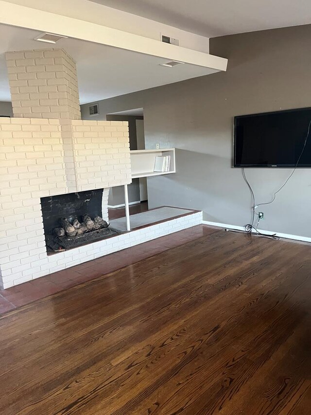 unfurnished living room featuring hardwood / wood-style floors and a brick fireplace