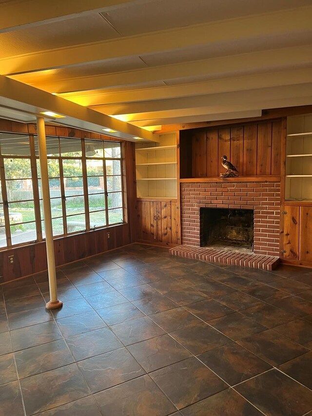 unfurnished living room with a wealth of natural light, built in features, a fireplace, and wood walls