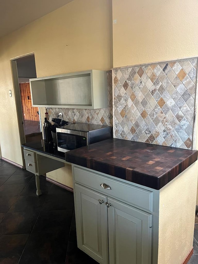 kitchen with backsplash, butcher block countertops, and dark tile patterned floors