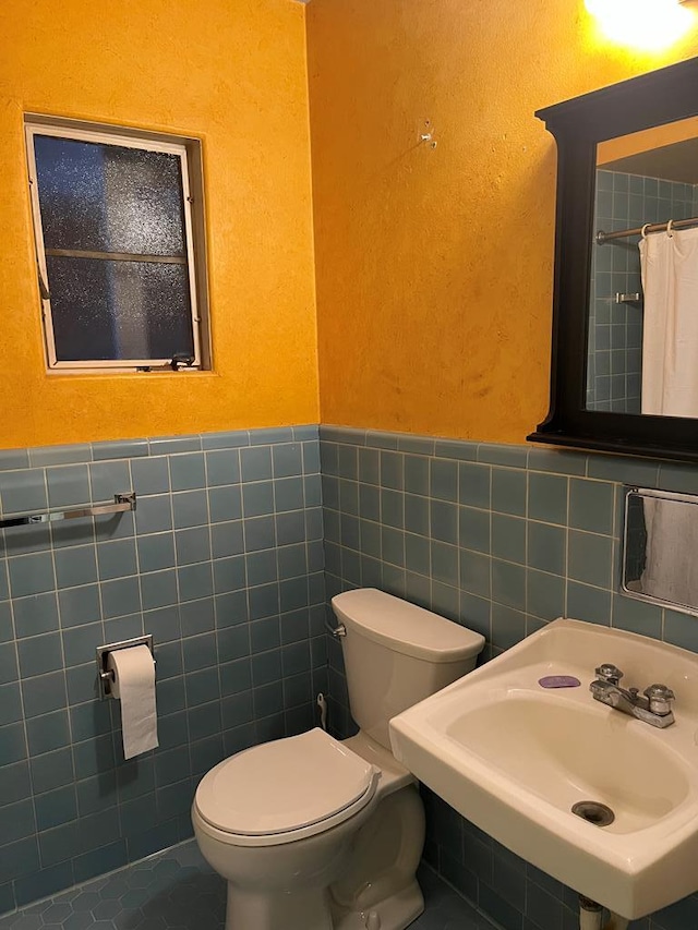 bathroom featuring tile walls, sink, and toilet