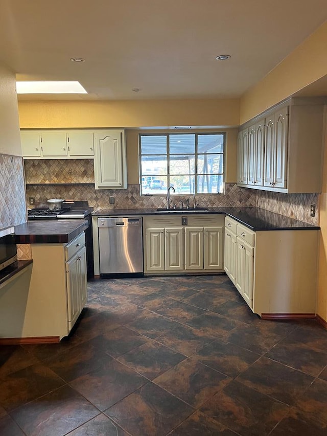 kitchen featuring dishwasher, sink, decorative backsplash, and a skylight