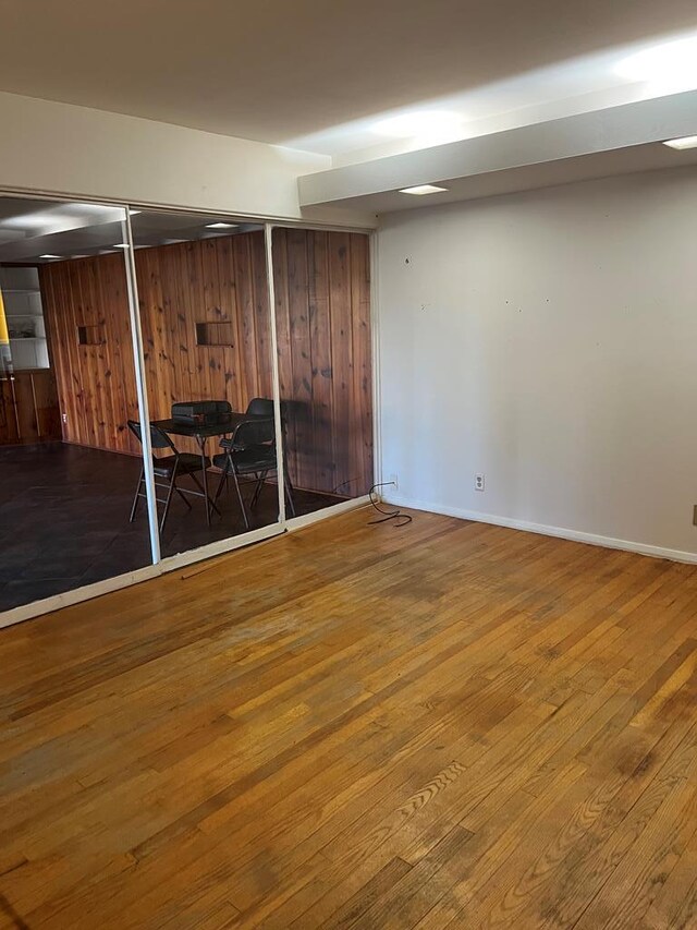 basement featuring hardwood / wood-style flooring and wooden walls