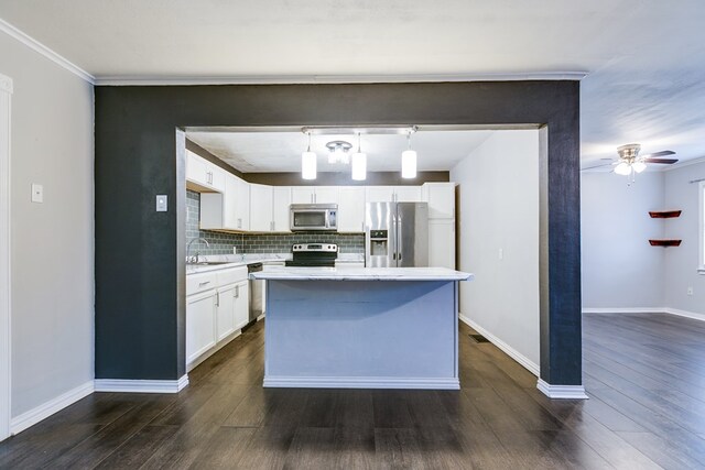 kitchen with appliances with stainless steel finishes, tasteful backsplash, sink, white cabinets, and hanging light fixtures