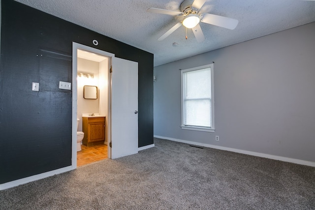 unfurnished bedroom featuring ceiling fan, ensuite bath, light carpet, and a textured ceiling