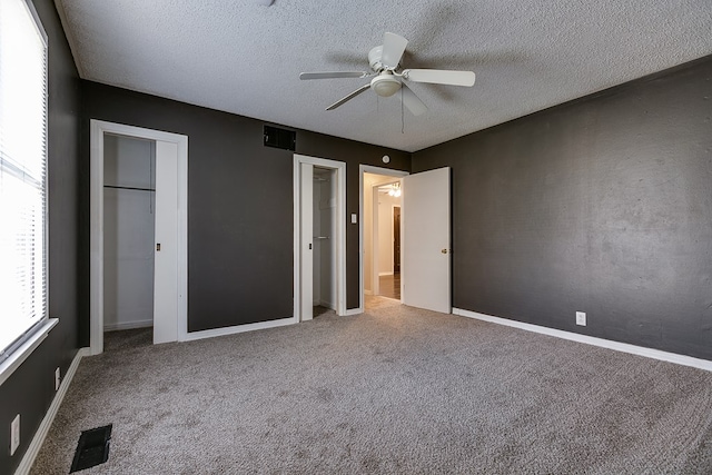 unfurnished bedroom with a textured ceiling, ceiling fan, and carpet flooring