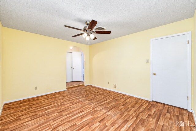 25 Dellwood Dr, San Angelo, TX 76903 - empty room with light wood finished floors, arched walkways, a ceiling fan, and a textured ceiling