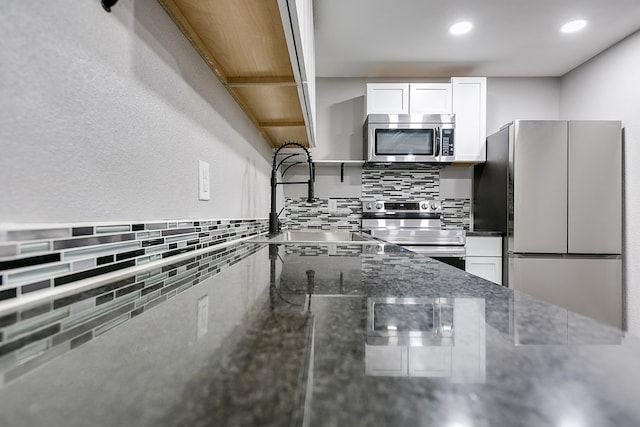 6622 Knickerbocker Rd, San Angelo, TX 76904 - kitchen with stainless steel appliances, tasteful backsplash, white cabinets, dark stone countertops, and recessed lighting