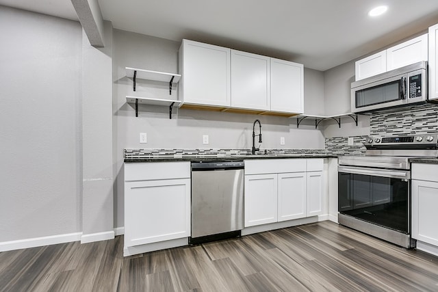 6622 Knickerbocker Rd, San Angelo, TX 76904 - kitchen featuring stainless steel appliances, open shelves, wood finished floors, dark countertops, and decorative backsplash
