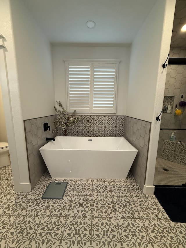 full bathroom featuring toilet, wainscoting, tile walls, and tile patterned floors