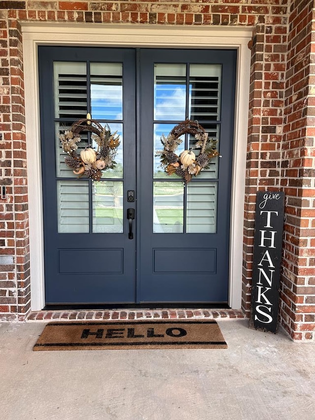 entrance to property featuring french doors and brick siding